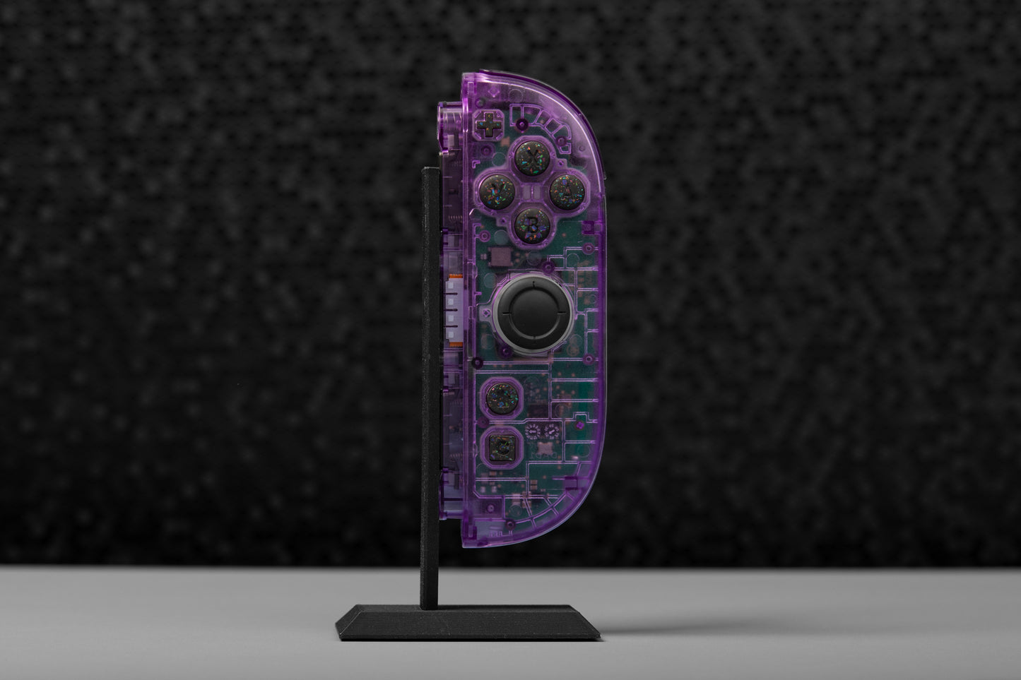 Purple joycon on a stand against a dark textured background